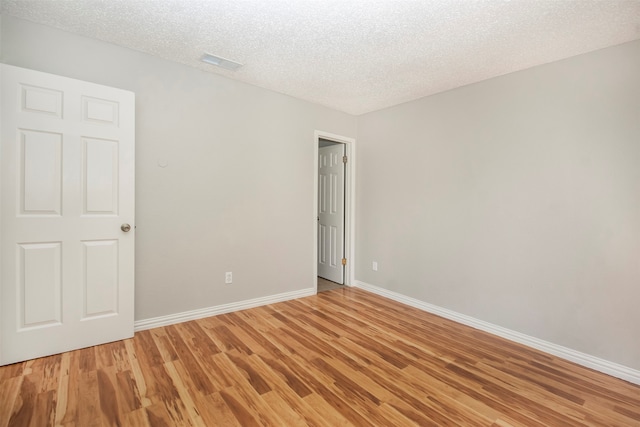 empty room featuring a textured ceiling and light hardwood / wood-style floors