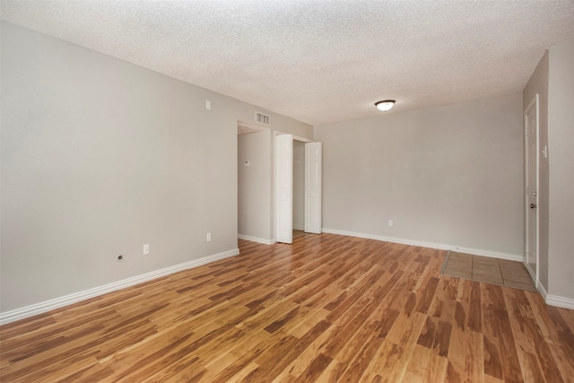 spare room with hardwood / wood-style floors and a textured ceiling