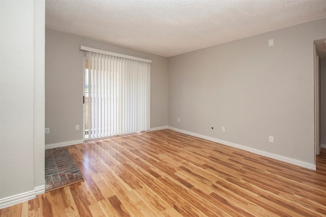 spare room featuring light hardwood / wood-style floors and a textured ceiling