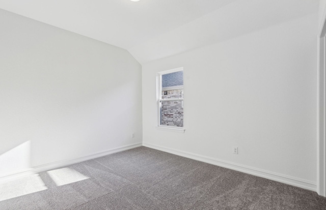 spare room with carpet and vaulted ceiling