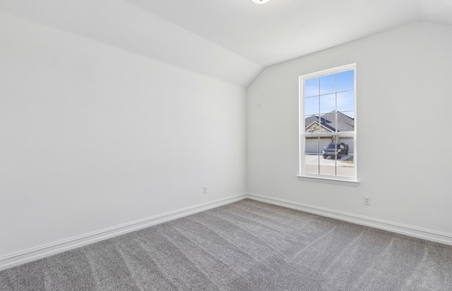 unfurnished room with vaulted ceiling and carpet floors