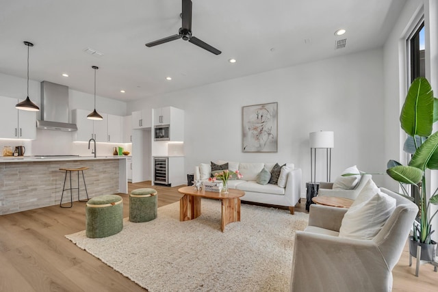 living room featuring light hardwood / wood-style flooring, beverage cooler, and ceiling fan