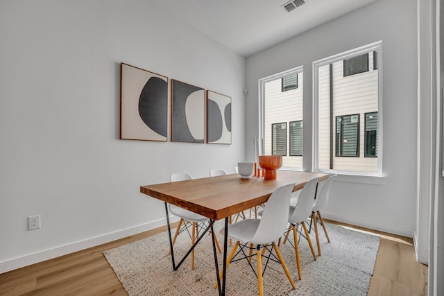 dining space with visible vents, light wood-style flooring, and baseboards