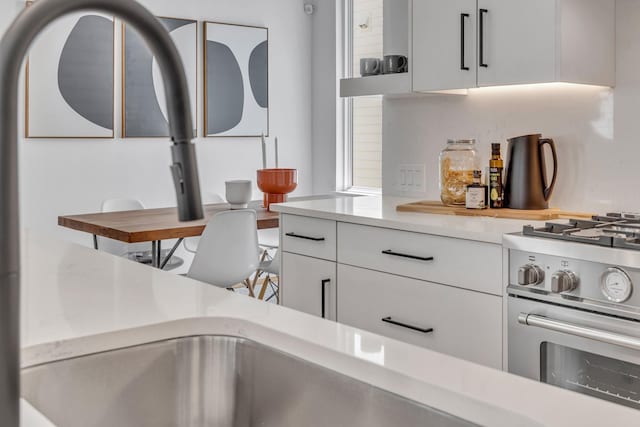 kitchen with light countertops, stainless steel range with gas stovetop, and white cabinetry