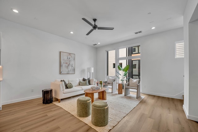 living room with light wood-style flooring, visible vents, baseboards, and recessed lighting