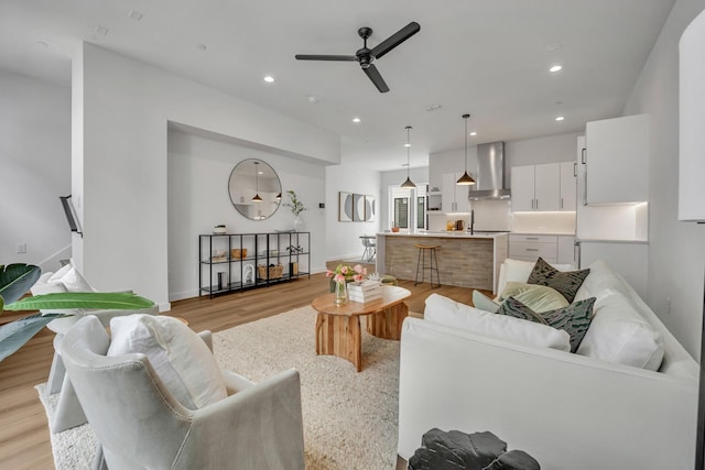 living room featuring baseboards, ceiling fan, light wood-style flooring, and recessed lighting