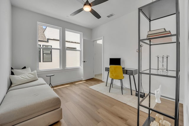 office featuring a ceiling fan, visible vents, baseboards, and wood finished floors