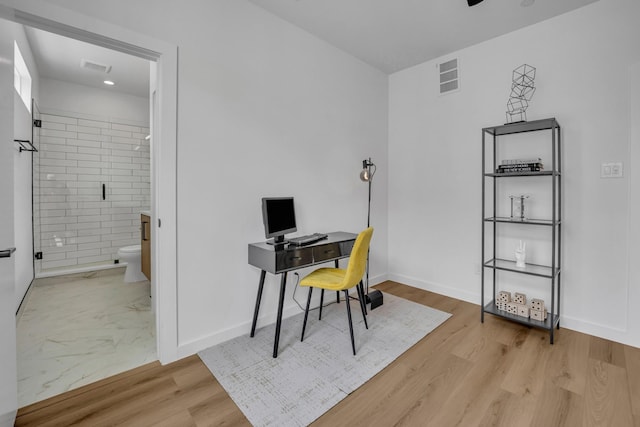 home office featuring light wood-type flooring, visible vents, and baseboards