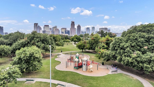 view of property's community with playground community, a lawn, and a city view