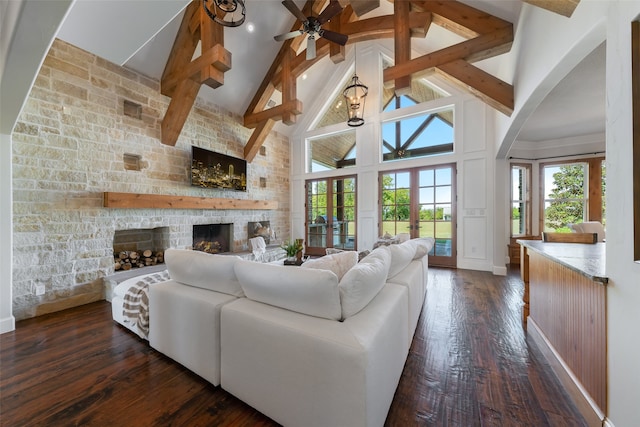 living room featuring high vaulted ceiling, a stone fireplace, dark hardwood / wood-style floors, ceiling fan, and beamed ceiling