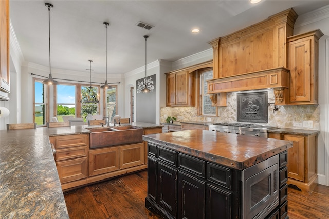 kitchen with a center island, dark stone counters, sink, hanging light fixtures, and dark hardwood / wood-style floors