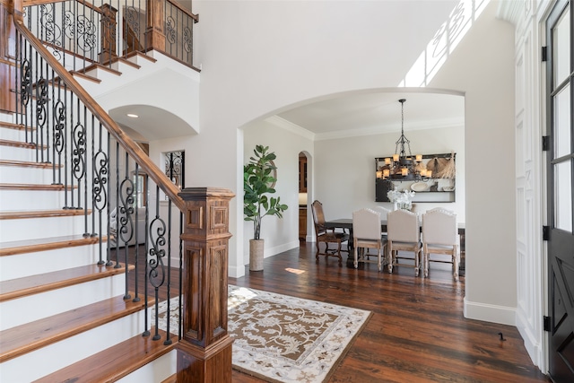 entryway featuring a high ceiling, dark hardwood / wood-style floors, an inviting chandelier, and ornamental molding