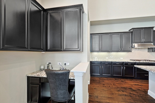 kitchen with light stone counters, dark hardwood / wood-style floors, stainless steel gas stovetop, and tasteful backsplash