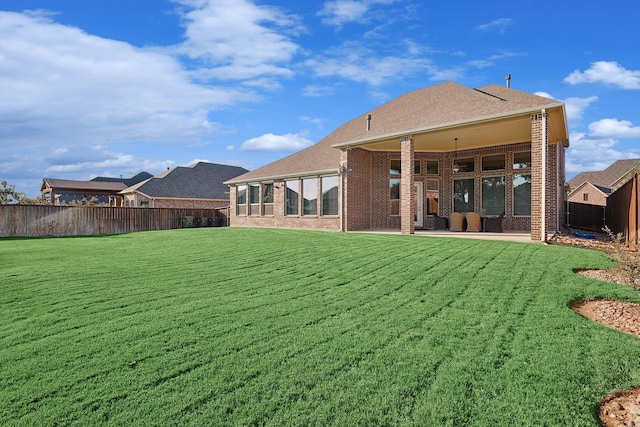 rear view of property featuring a patio area, a lawn, and ceiling fan