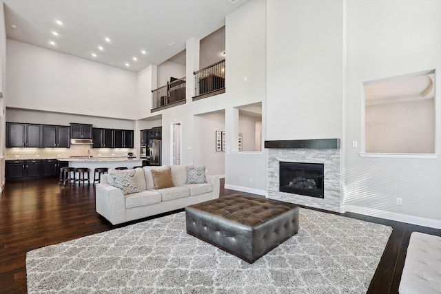 living room with a towering ceiling, dark hardwood / wood-style floors, and a fireplace