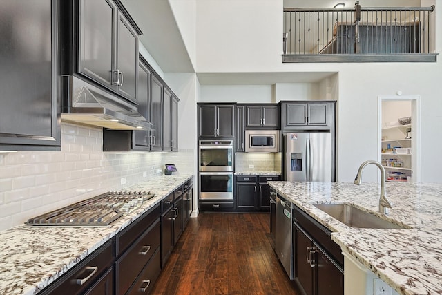 kitchen featuring light stone counters, sink, appliances with stainless steel finishes, dark hardwood / wood-style floors, and decorative backsplash