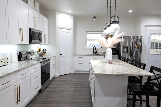 kitchen with appliances with stainless steel finishes, plenty of natural light, a kitchen breakfast bar, and white cabinetry