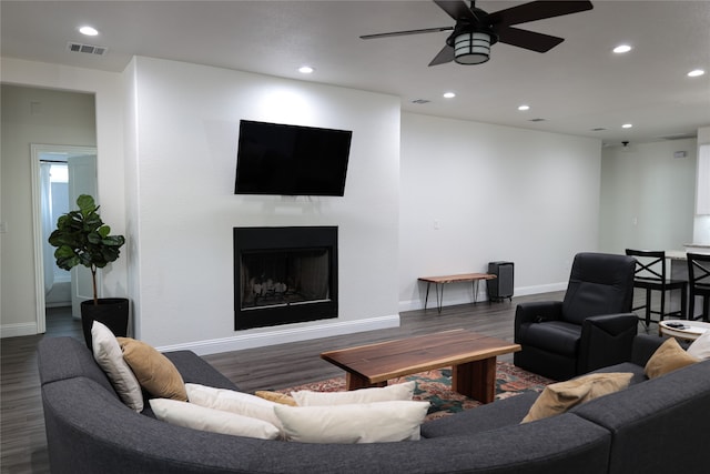 living room featuring ceiling fan and dark wood-type flooring