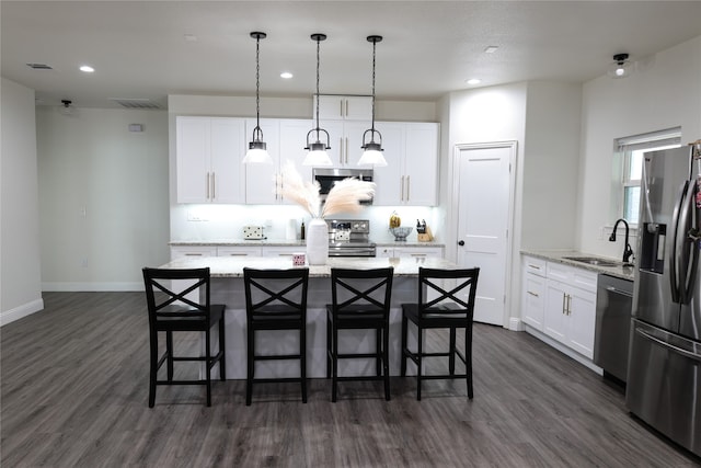 kitchen with a kitchen island with sink, sink, pendant lighting, white cabinetry, and appliances with stainless steel finishes