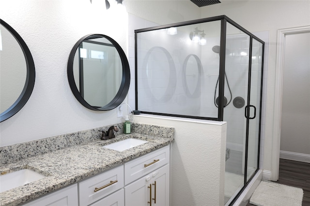 bathroom with hardwood / wood-style floors, a shower with shower door, and vanity