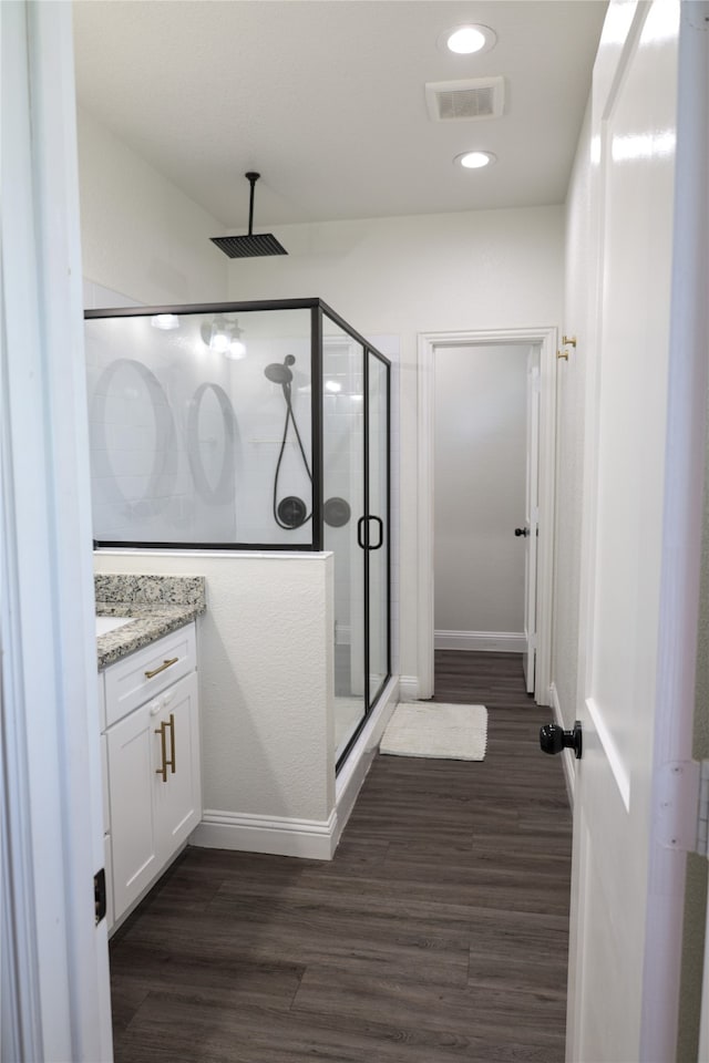 bathroom with hardwood / wood-style flooring, a shower with door, and vanity