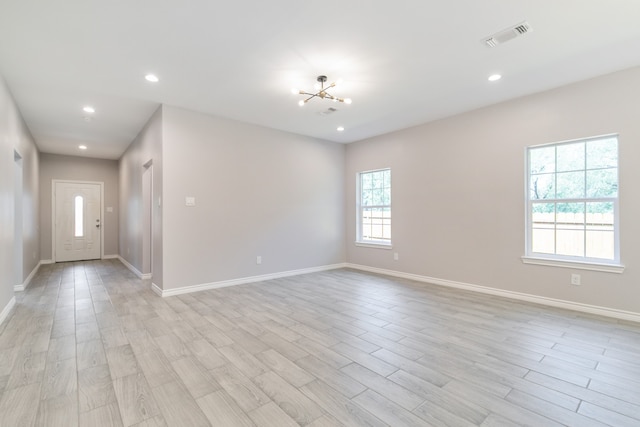 spare room featuring light hardwood / wood-style floors and a chandelier