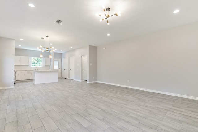 unfurnished living room featuring light hardwood / wood-style floors and a chandelier