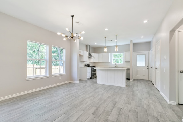 kitchen with decorative light fixtures, wall chimney range hood, white cabinetry, stainless steel appliances, and a center island