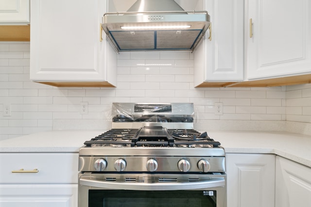 kitchen featuring extractor fan, decorative backsplash, stainless steel range, and white cabinets