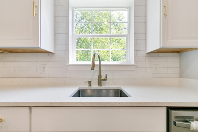 kitchen featuring light stone counters, sink, decorative backsplash, and white cabinetry