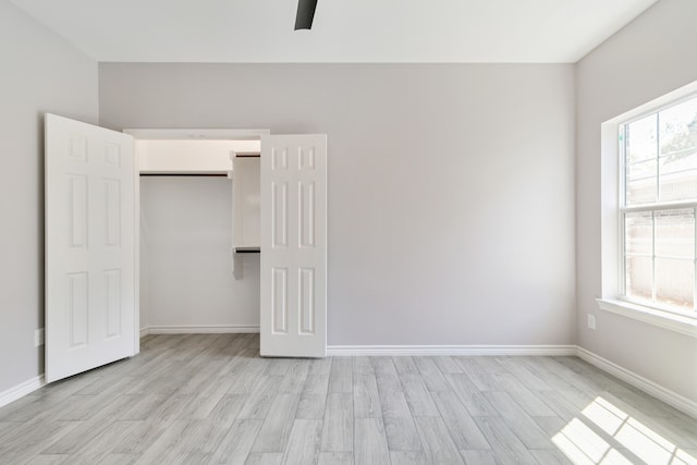 unfurnished bedroom featuring light wood-type flooring, multiple windows, and ceiling fan