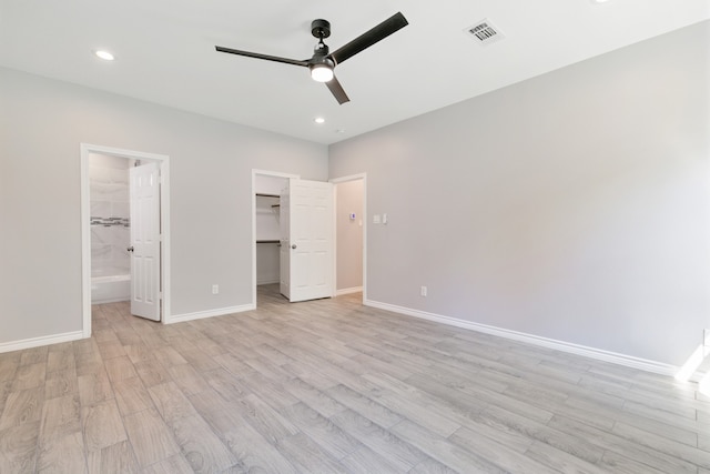 unfurnished bedroom featuring light wood-type flooring, ceiling fan, connected bathroom, and a walk in closet