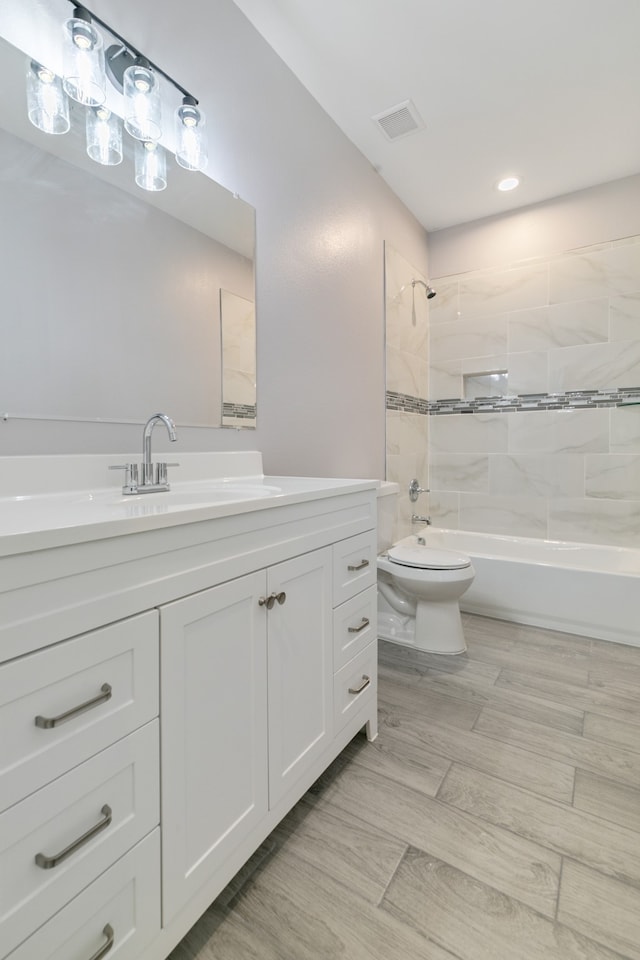 full bathroom with tiled shower / bath, vanity, and toilet