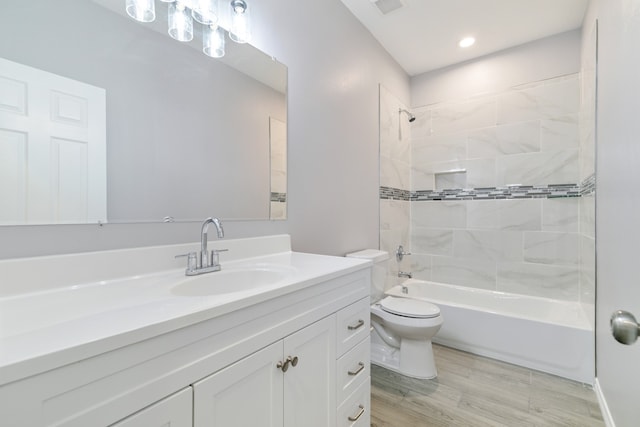 full bathroom with hardwood / wood-style floors, vanity, tiled shower / bath combo, and toilet