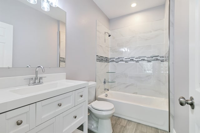 full bathroom featuring vanity, tiled shower / bath combo, toilet, and hardwood / wood-style flooring