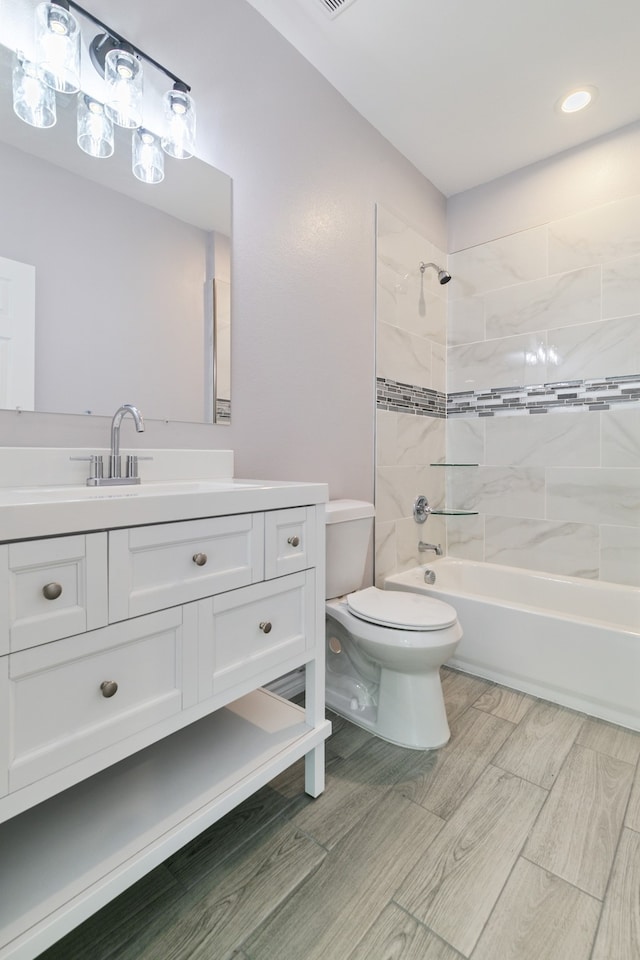 full bathroom with hardwood / wood-style floors, toilet, vanity, and tiled shower / bath combo