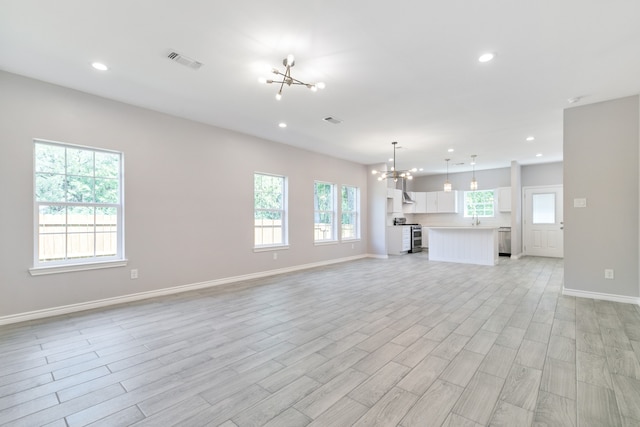 unfurnished living room featuring light hardwood / wood-style floors, a notable chandelier, and sink