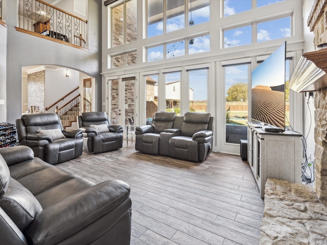 living room with a healthy amount of sunlight, a high ceiling, and light hardwood / wood-style flooring