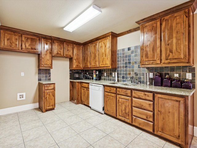 kitchen featuring dishwasher, backsplash, sink, light tile patterned flooring, and light stone counters