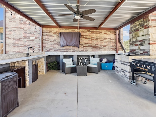 view of patio / terrace with a fireplace, an outdoor kitchen, ceiling fan, and sink