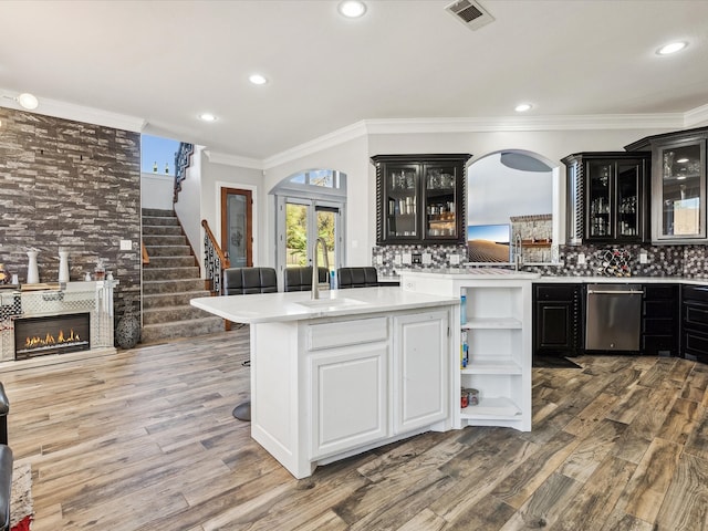 kitchen with backsplash, dishwasher, sink, and wood-type flooring