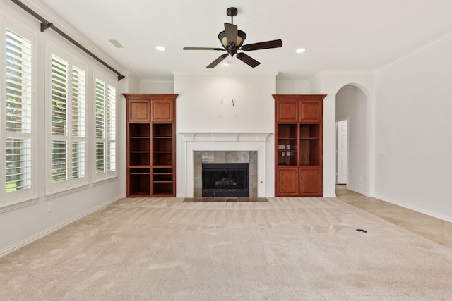 unfurnished living room featuring crown molding, ceiling fan, light colored carpet, and a fireplace