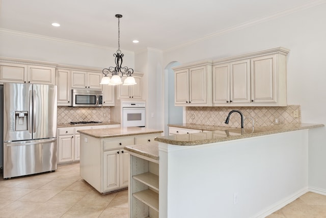 kitchen with kitchen peninsula, hanging light fixtures, appliances with stainless steel finishes, and cream cabinets