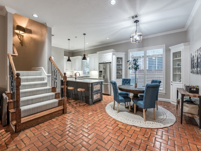 dining area featuring crown molding, a chandelier, and sink