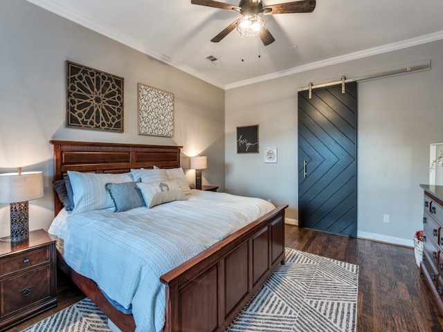 bedroom featuring a barn door, ornamental molding, dark hardwood / wood-style flooring, and ceiling fan