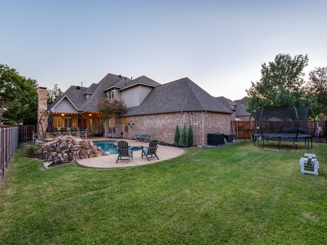 yard at dusk featuring a trampoline, a fenced in pool, and a patio