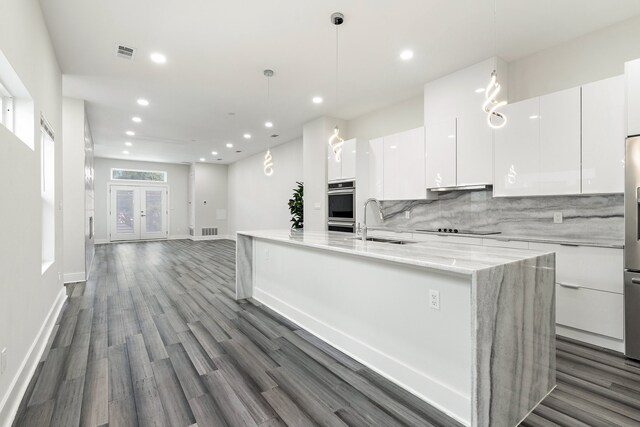 kitchen with sink, decorative light fixtures, white cabinetry, dark hardwood / wood-style floors, and decorative backsplash