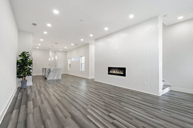 unfurnished living room featuring a fireplace, dark hardwood / wood-style flooring, and sink