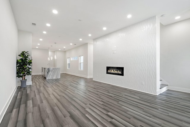 2507 Crossman Ave, Dallas, TX 75212 - unfurnished living room featuring wood finished floors, recessed lighting, baseboards, a tiled fireplace, and stairway