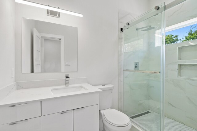 bathroom featuring a shower with shower door, vanity, and toilet